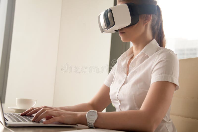 Young girl wearing VR headset and typing on laptop stock photos Young girl wearing VR headset and typing on laptop stock photos