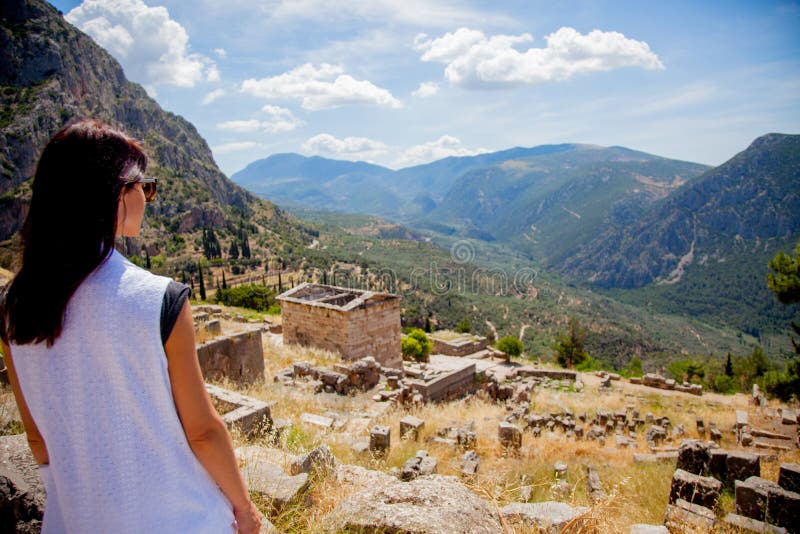 Young girl in white clothes standing on rock in Greece