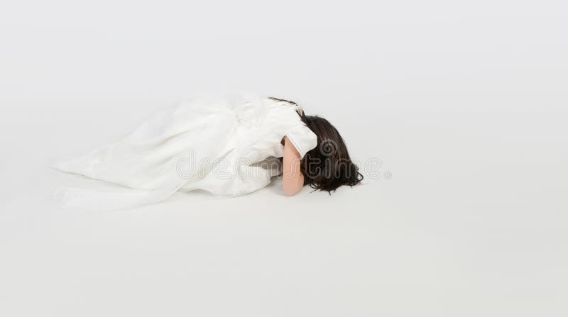 Young girl in white dress prostrate on the floor.