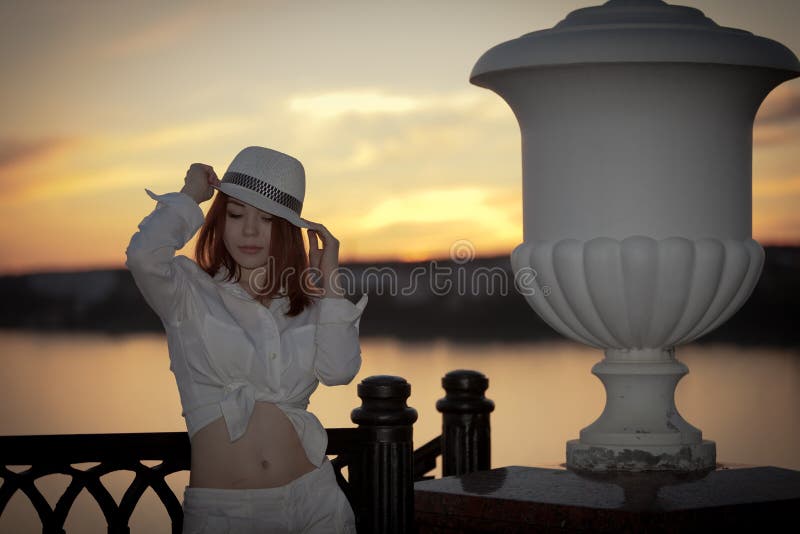 Giovane ragazza in una camicia bianca e cappello, nel tramonto.