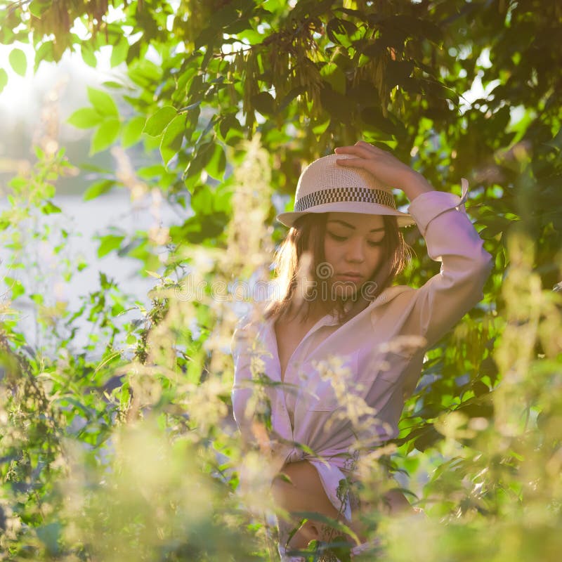 Mladá dívka v bílé košili a klobouk, v západu slunce.