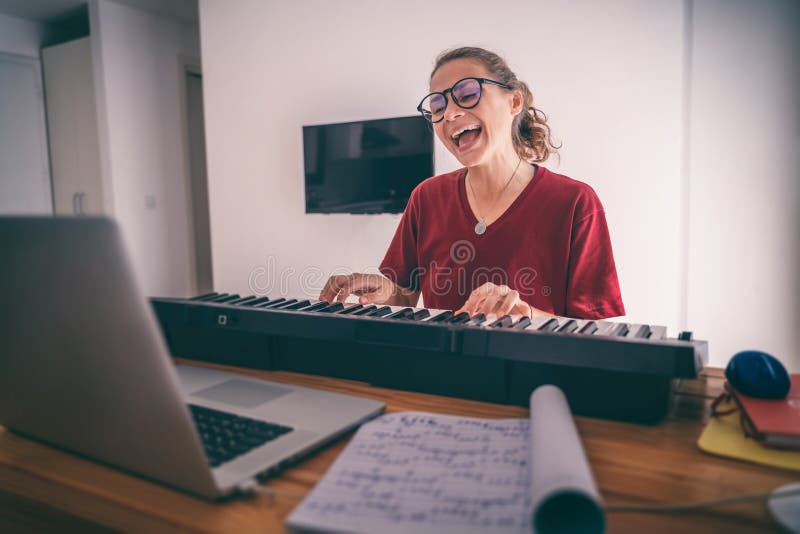 Young girl woman learns to sing and play the piano from a video conference from a laptop in internet. Education video calls self