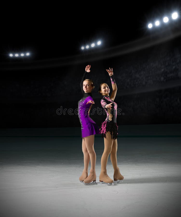 Young girls figure skaters on ice arena with spotlights ver