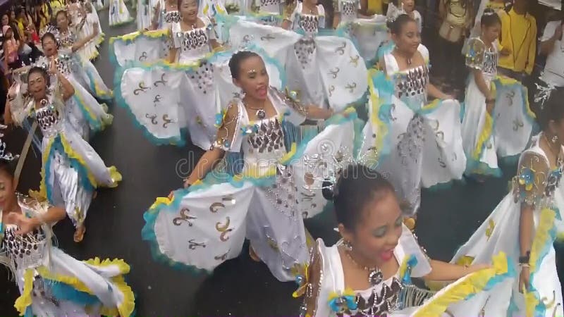 Young girls in ornate butterfly costume dance along the street, a festival to honor a patron saint
