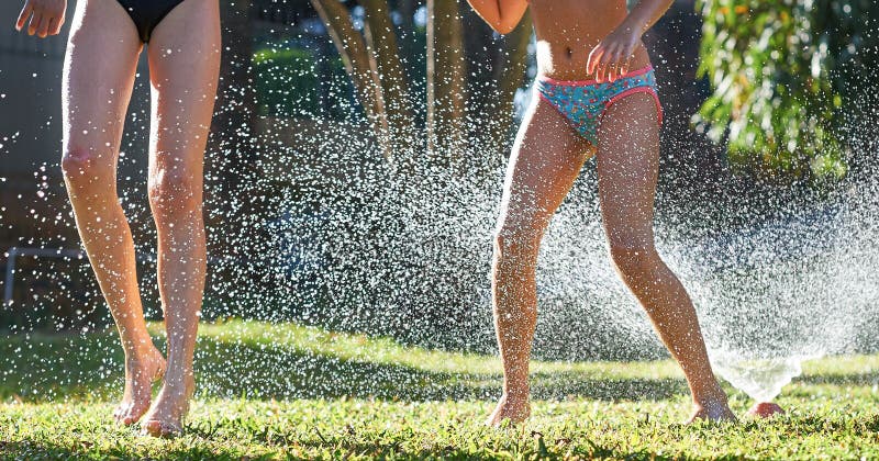 young girls playing jumping garden water lawn sprinkler 75628311