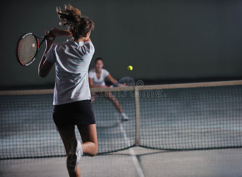 Mladé dívky hrát tenis hry indoori ve tenisový kurt.