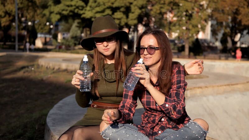 Young girls are sitting in the park, they say, have fun and eat, eat a sandwich. Fun, laughter, holiday