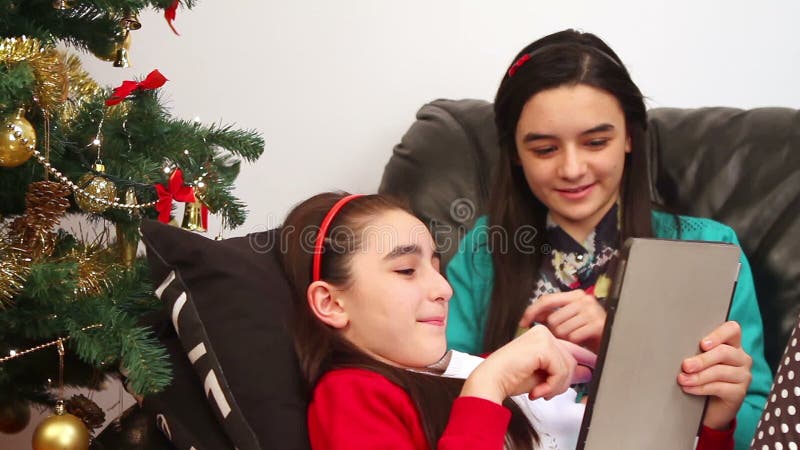 Young girls using a digital tablet near Christmas tree