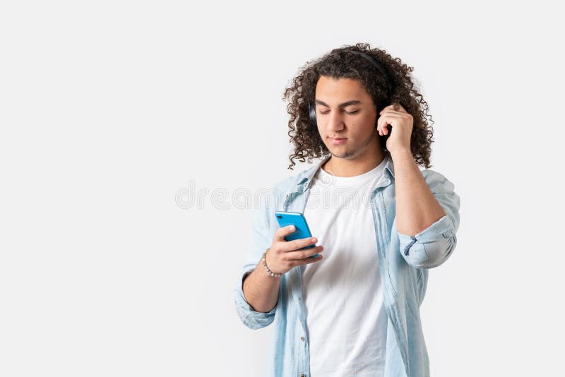 Young good looking man with headphones listening the music from his smart phone, isolated white background. stock photos Young good looking man with headphones listening the music from his smart phone, isolated white background. stock photos
