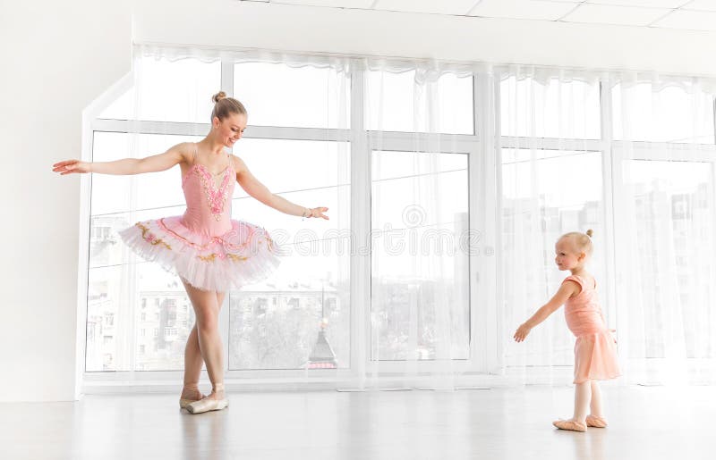 Young gorgeous ballerina with her little daughter dancing in studio stock photo Young gorgeous ballerina with her little daughter dancing in studio stock photo