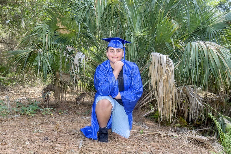 Young Graduate Proudly Posing In Front Of A Fan Palm With Cap And Gown stock images Young Graduate Proudly Posing In Front Of A Fan Palm With Cap And Gown stock images