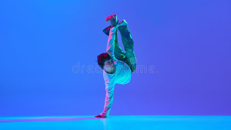 Young guy, breakdancer in action, expressing passion and movement through powerful performance against gradient blue royalty free stock images