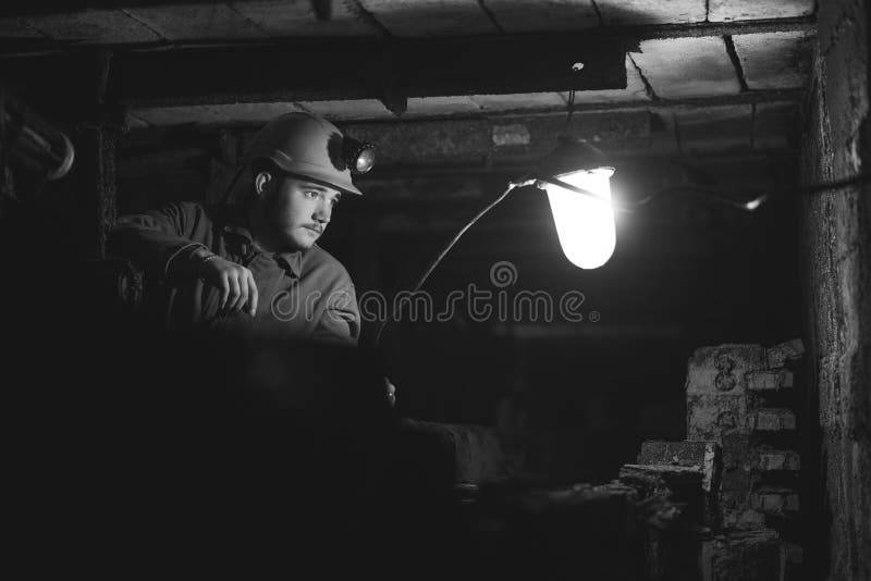 A young guy in a protective suit and helmet sits in a tunnel with a burning scrapbook stock photography A young guy in a protective suit and helmet sits in a tunnel with a burning scrapbook stock photography