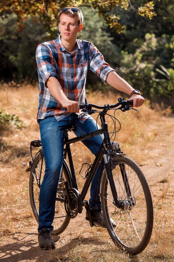 The Young Guy Sits on Bicycle. Stock Photo Image of ride, biker 75555642