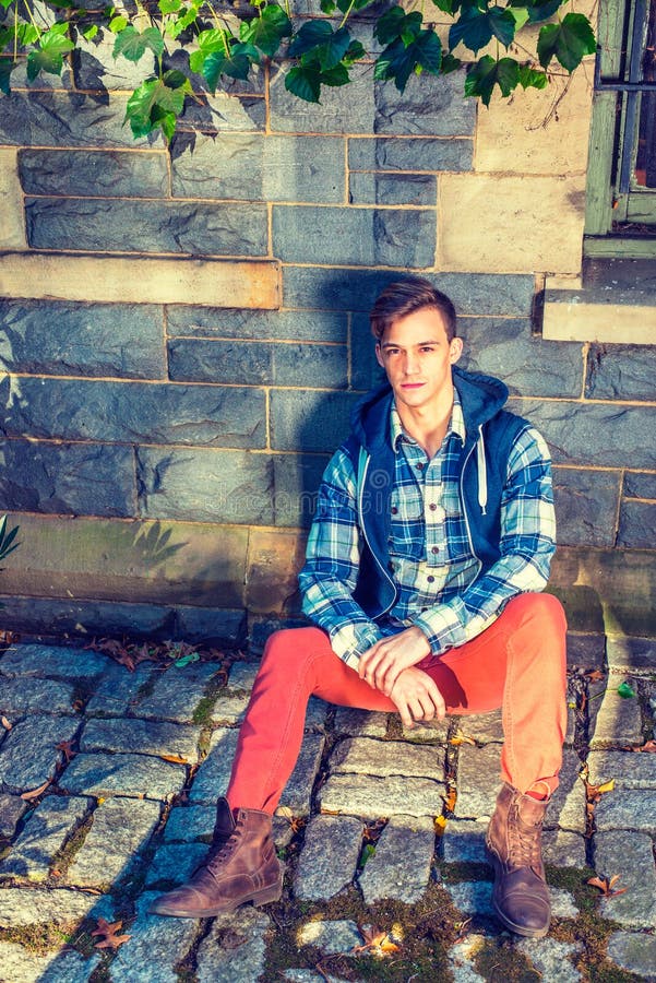 A Young Guy is Sitting on the Ground Against the Wall with Ivy Leaves ...