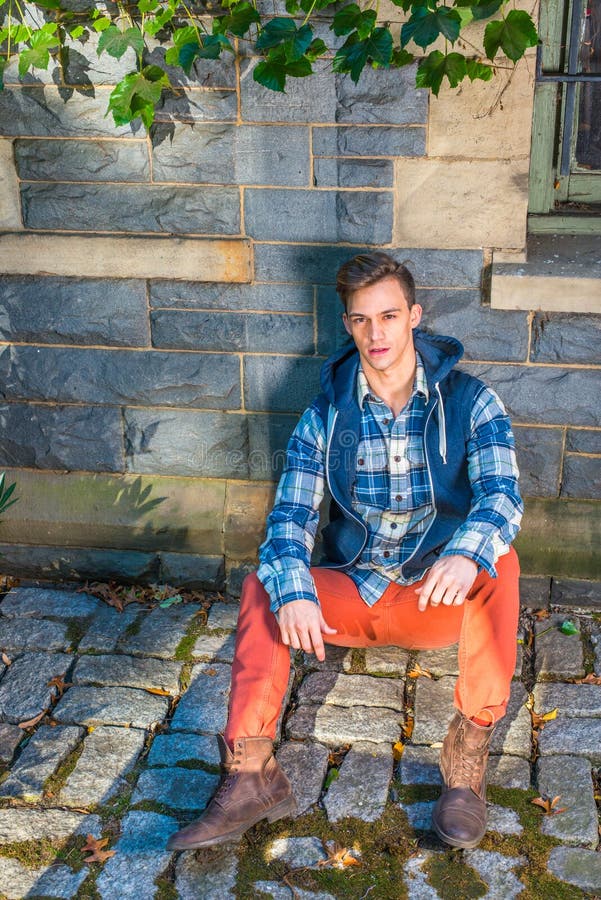 A Young Guy is Sitting on the Ground Against the Wall with Ivy Leaves ...