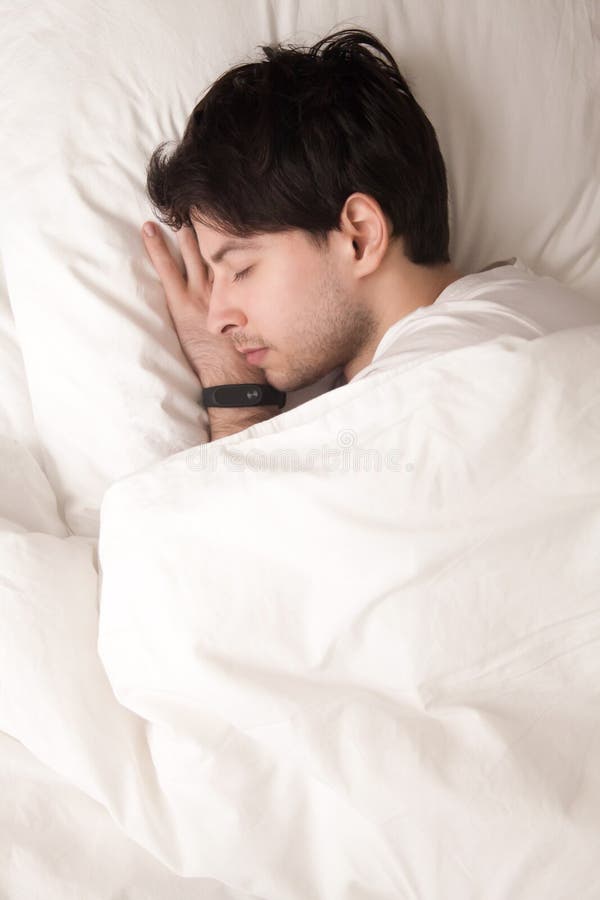 Young guy sleeping in bed wearing smart watch, sleep tracker