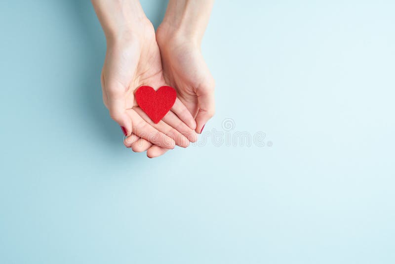 A person holding red heart in hands, donate and family insurance concept, on aquamarine background, copy space top view royalty free stock photography