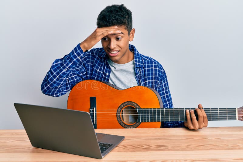 Young handsome african american man learning classical guitar from online tutorial stressed and frustrated with hand on head royalty free stock photos