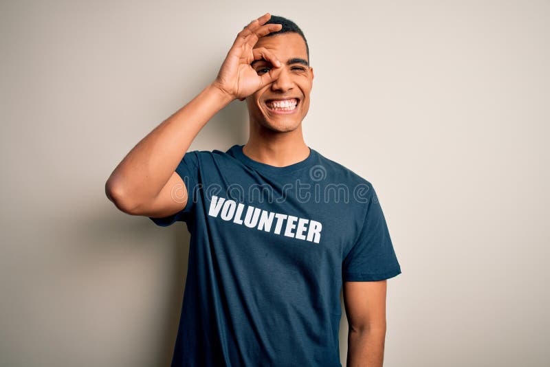 Young handsome african american man volunteering wearing t-shirt with volunteer message doing ok gesture with hand smiling, eye