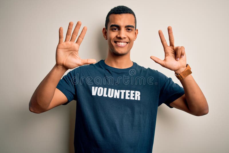 Young handsome african american man volunteering wearing t-shirt with volunteer message showing and pointing up with fingers