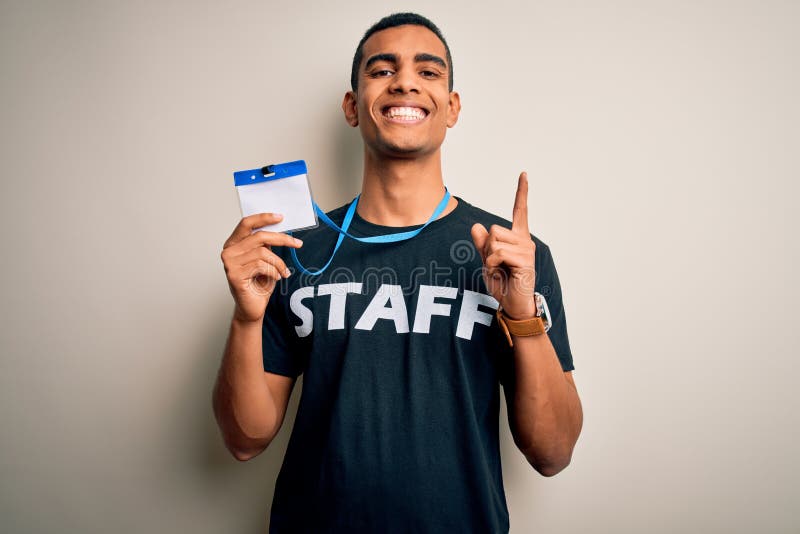 Young handsome african american worker man wearing staff uniform holding id card surprised with an idea or question pointing