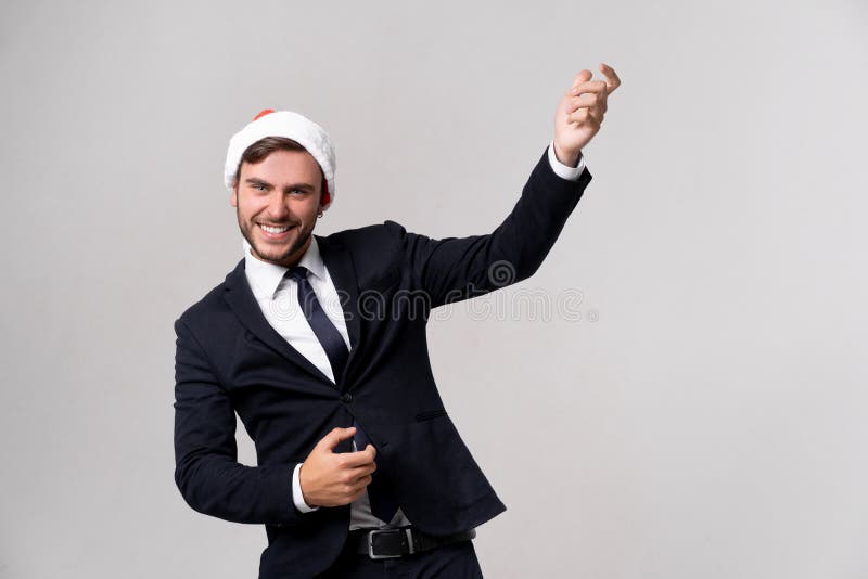 Young handsome caucasian guy in business suit and Santa hats stands on white background in studio and Plays on an imaginary guitar