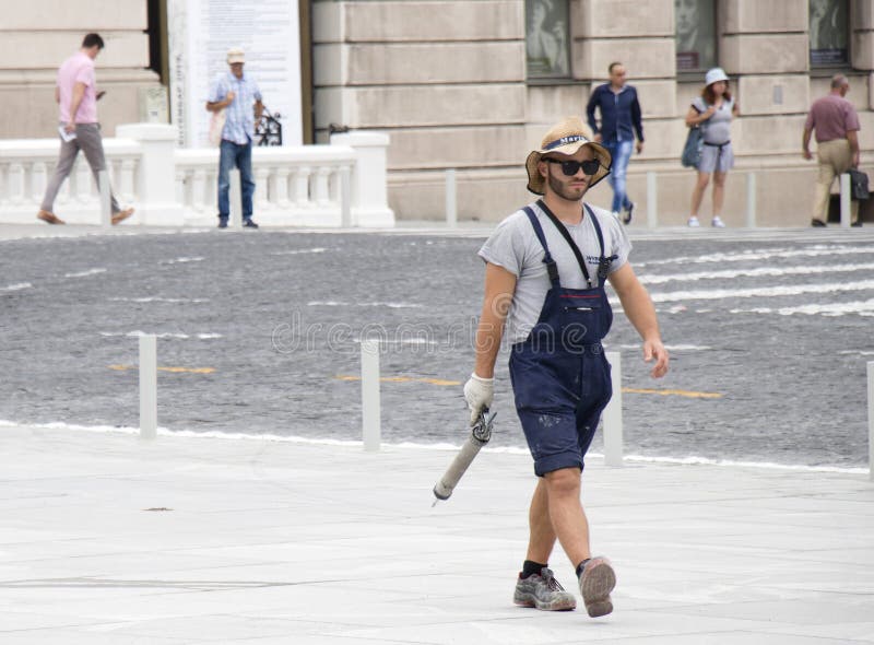 Young and handsome construction worker in casual summer outfit on city pavement holding a caulking gun stock image Young and handsome construction worker in casual summer outfit on city pavement holding a caulking gun stock image