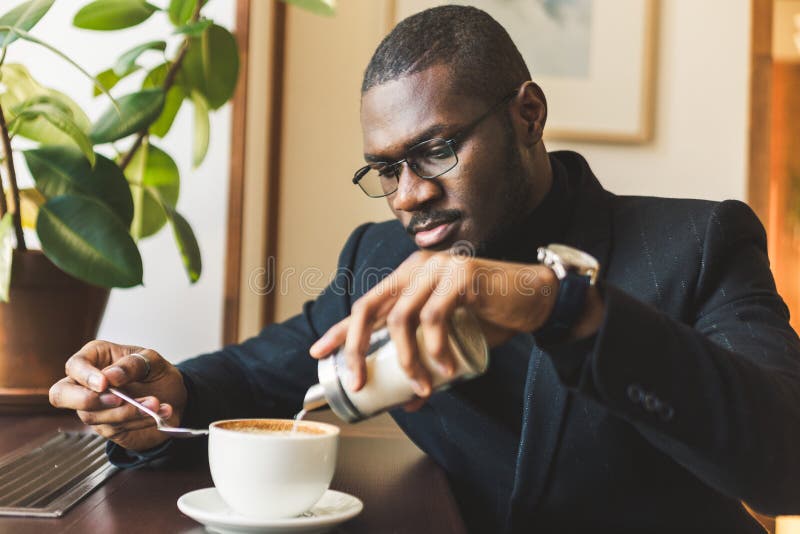 Young handsome dark-skinned businessman drinks coffee in a cafe. royalty free stock images Young handsome dark-skinned businessman drinks coffee in a cafe. royalty free stock images