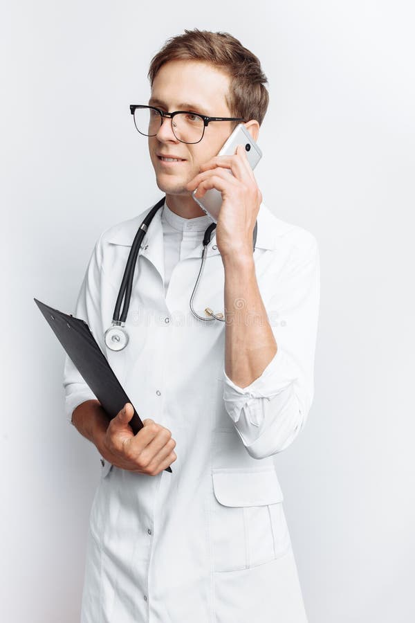 Young and handsome doctor talking on the phone with patients, Intern student with folder in hand, white background, for advertisin stock image Young and handsome doctor talking on the phone with patients, Intern student with folder in hand, white background, for advertisin stock image