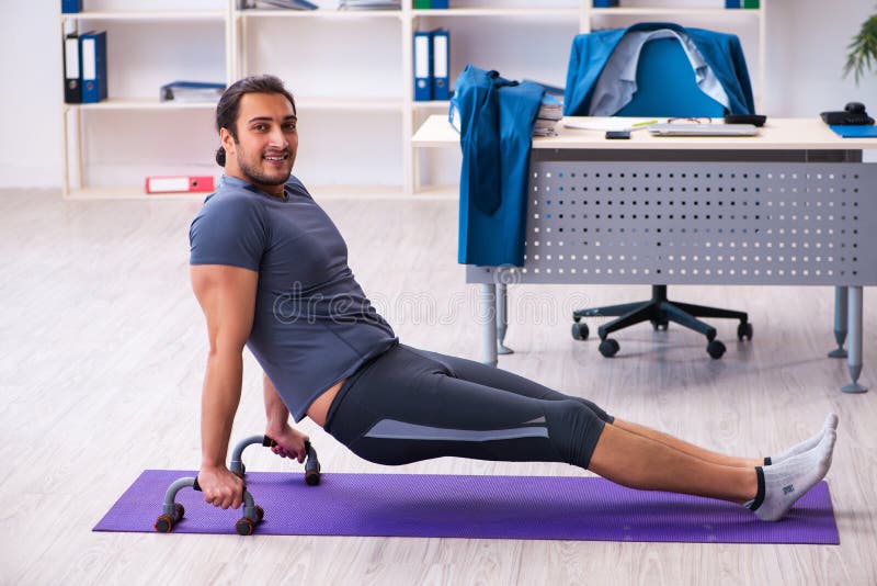 Young Handsome Employee Doing Sport Exercises in the Office Stock Photo