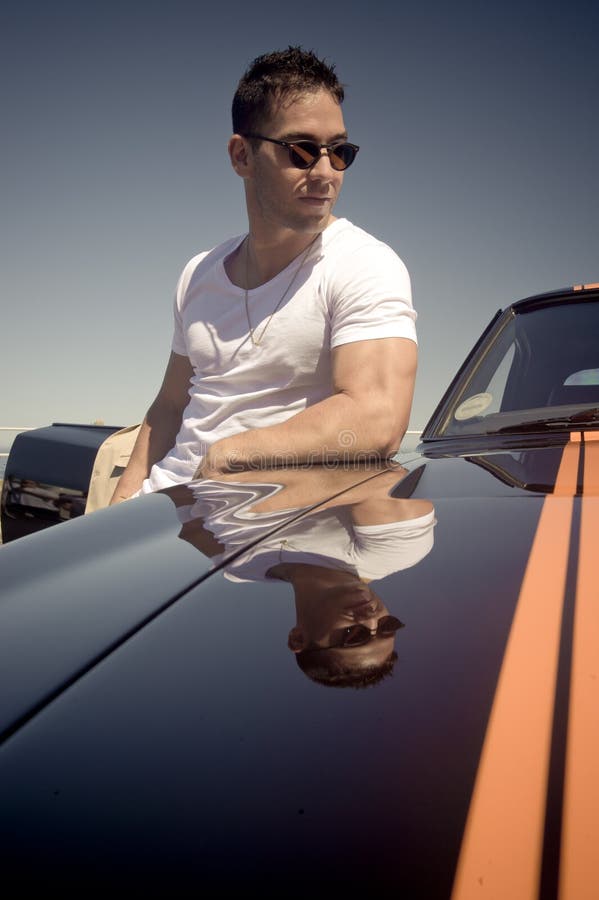 Young handsome guy leaning on muscle car with stripes