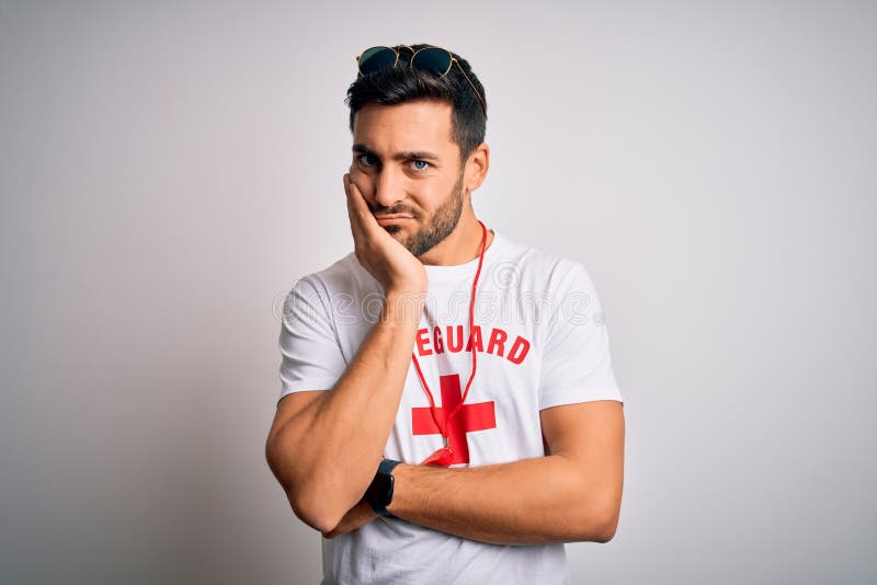 Young handsome lifeguard man with beard wearing t-shirt with red cross and whistle thinking looking tired and bored with