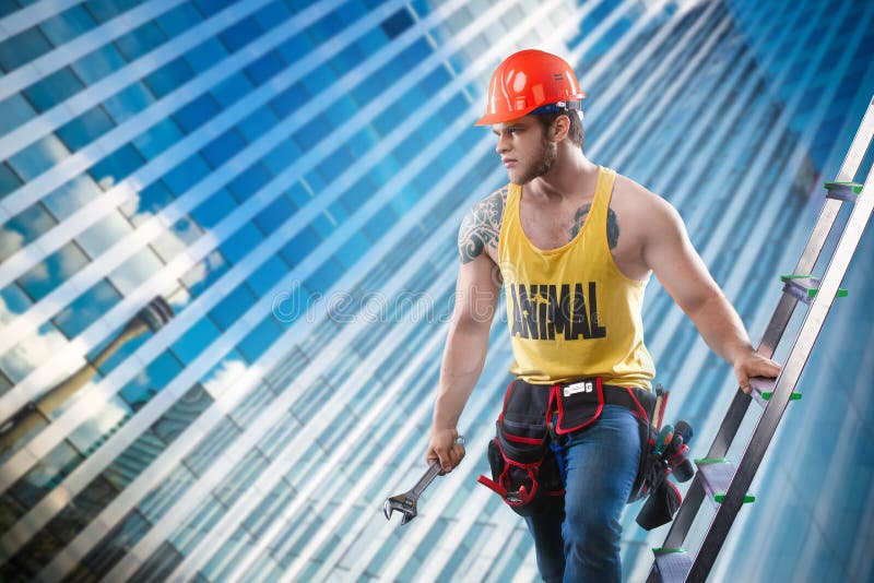 Young handsome macho man builder with muscular athletic strong body in orange hard hat or helmet holds wrench near wood ladde stock image Young handsome macho man builder with muscular athletic strong body in orange hard hat or helmet holds wrench near wood ladde stock image