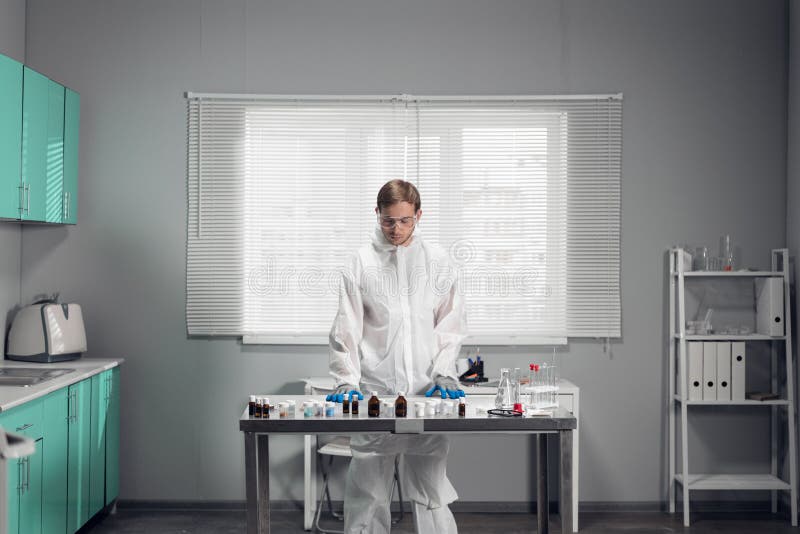 Young handsome male chemist working in a bright lab stock image
