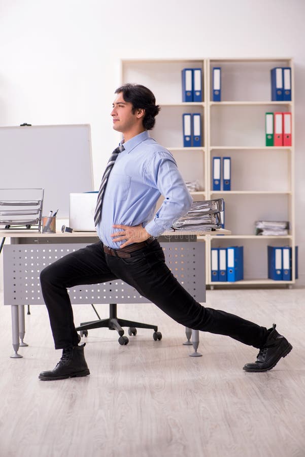 The young handsome male employee doing exercises in the office stock images The young handsome male employee doing exercises in the office stock images