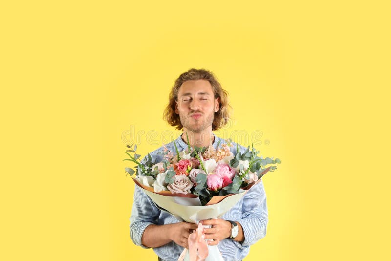 Young handsome man with beautiful flower bouquet on background