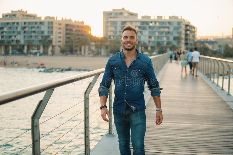 A young handsome man on the bridge near beautiful beach. stock photo A young handsome man on the bridge near beautiful beach. stock photo