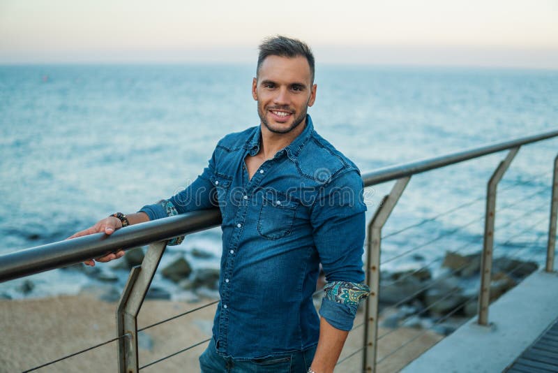 A young handsome man on the bridge near beautiful beach. stock photo A young handsome man on the bridge near beautiful beach. stock photo
