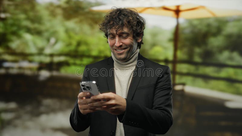 Young handsome man with phone smiling outdoors in park during daytime creating joyful atmosphere surrounded by greenery royalty free stock image