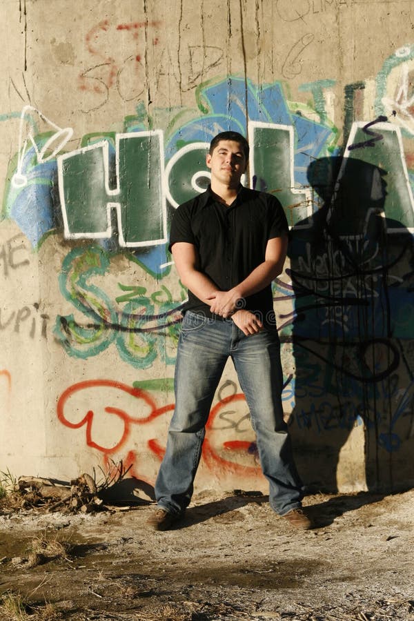 Young handsome man standing by the graffiti wall