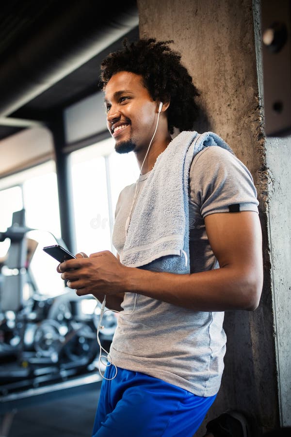 Young Handsome Man Using Phone while Having Exercise Break in Gym Stock