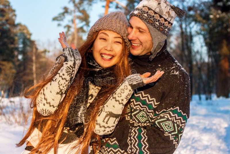 A young handsome man of European appearance and a young Asian girl in a park on the nature in winter