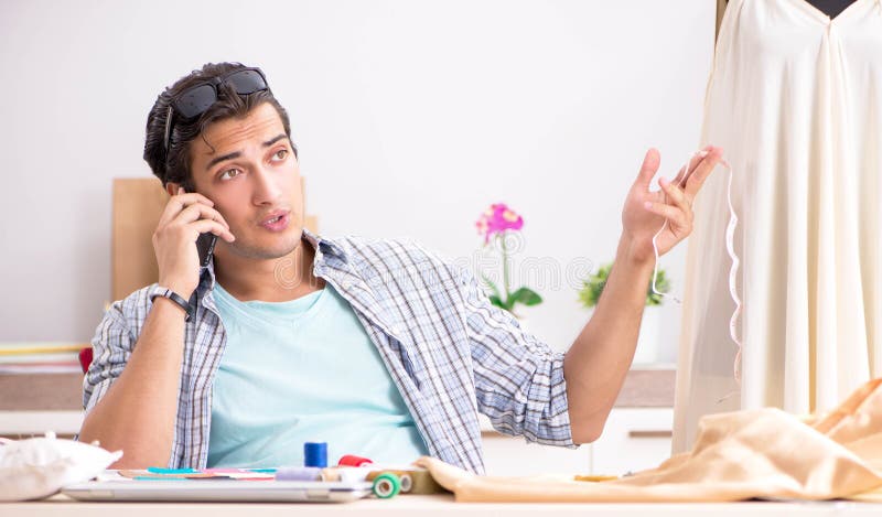 Young handsome tailor working in his workshop stock image