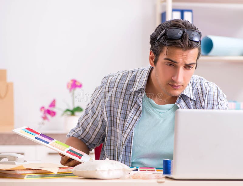 Young handsome tailor working in his workshop stock image