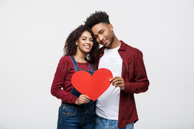 Young happy African American couple in love holding red paper heart.