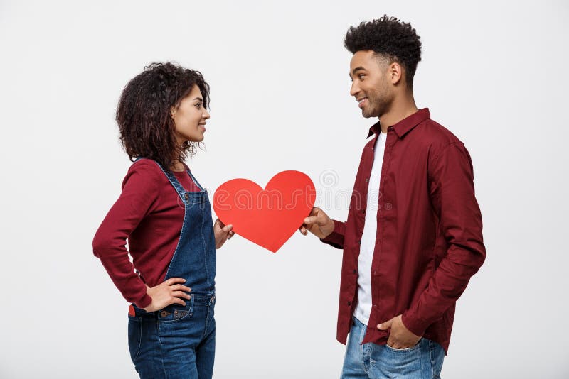 Young happy african american couple in love holding red paper heart.