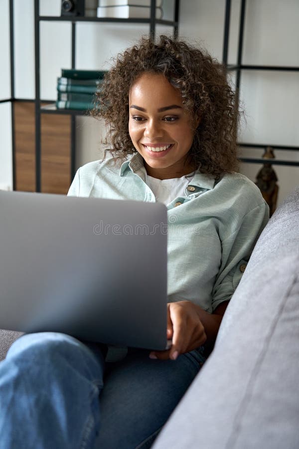 Happy Mixed Race Female Student Sitting on Soft Couch at Home Typing image image