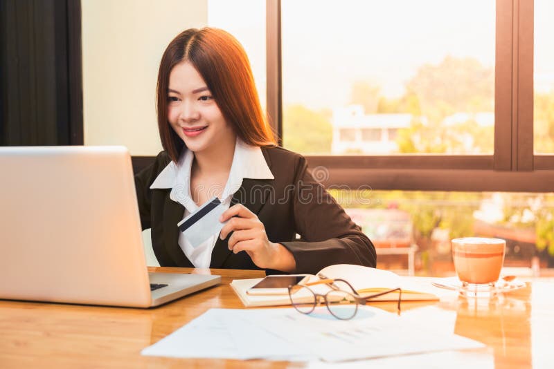Young happy asian business woman holding credit card and shopping online on her laptop computer royalty free stock image Young happy asian business woman holding credit card and shopping online on her laptop computer royalty free stock image