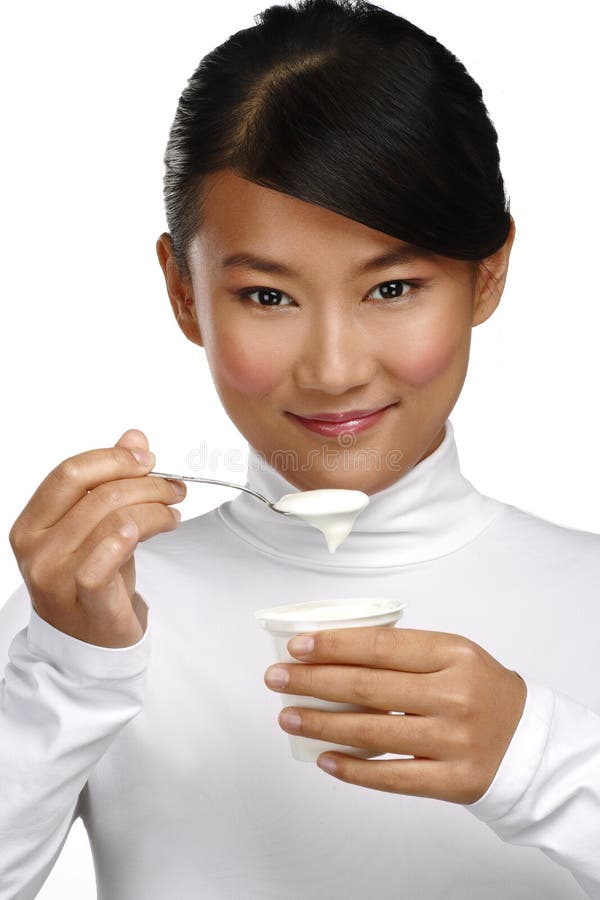 Young happy asian woman eating fresh yogurt